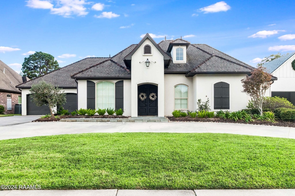 french country home with a front lawn and a garage