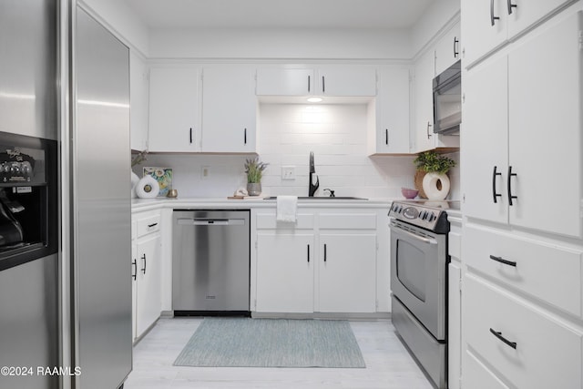 kitchen with sink, stainless steel appliances, light hardwood / wood-style flooring, decorative backsplash, and white cabinets