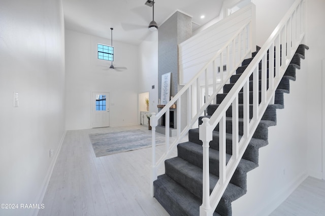 staircase featuring hardwood / wood-style floors, ceiling fan, and a high ceiling