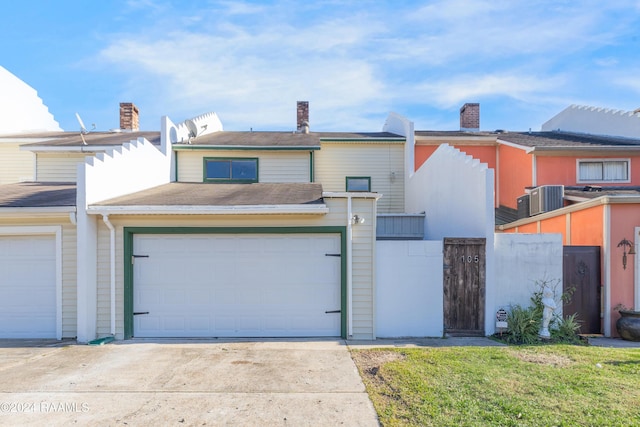 view of front of property with central AC, a front yard, and a garage