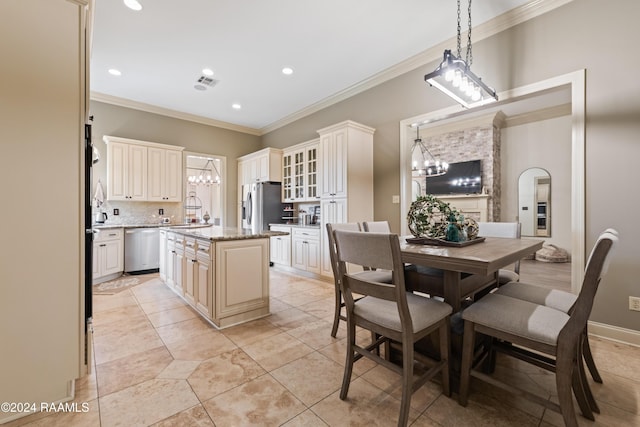 kitchen with appliances with stainless steel finishes, crown molding, stone counters, a center island, and hanging light fixtures