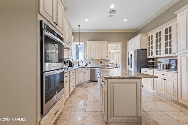 kitchen featuring light stone countertops, appliances with stainless steel finishes, backsplash, ornamental molding, and a center island