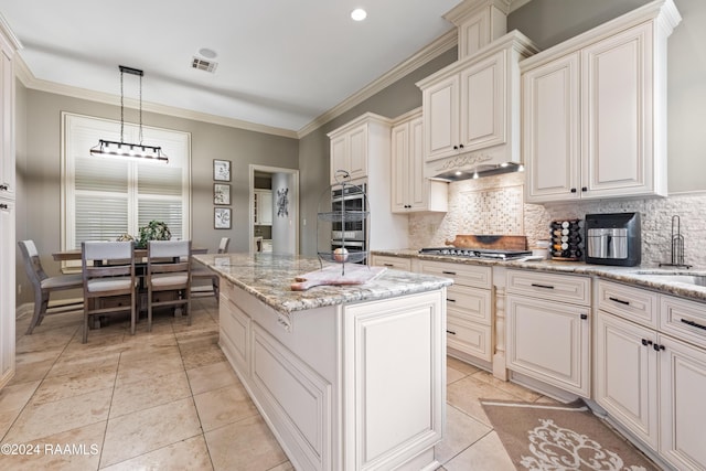 kitchen with a center island, hanging light fixtures, tasteful backsplash, light stone counters, and light tile patterned flooring