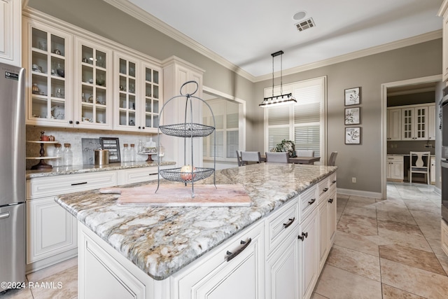 kitchen with stainless steel fridge, light stone counters, pendant lighting, a center island, and white cabinetry