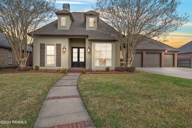 view of front of home with a garage, a yard, and french doors