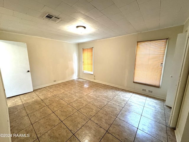 tiled spare room featuring ornamental molding