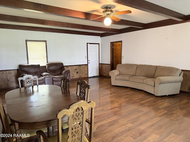 dining space featuring beam ceiling, ceiling fan, wood-type flooring, and wood walls