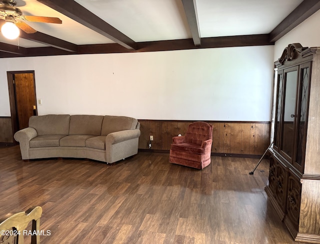 living room featuring beamed ceiling, ceiling fan, wood walls, and dark wood-type flooring