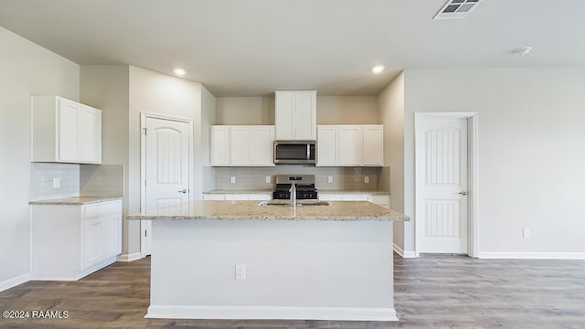 kitchen with wood-type flooring, white cabinetry, stainless steel appliances, and an island with sink