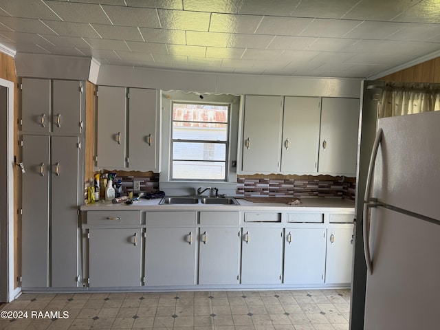 kitchen featuring white refrigerator, backsplash, and sink