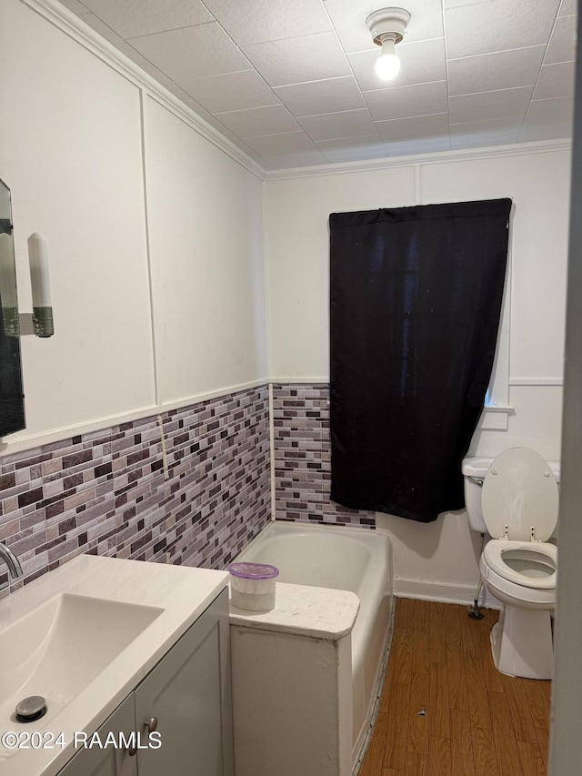 bathroom with crown molding, toilet, a bathtub, vanity, and hardwood / wood-style flooring