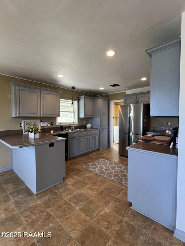 kitchen featuring pendant lighting, sink, gray cabinets, and stainless steel refrigerator