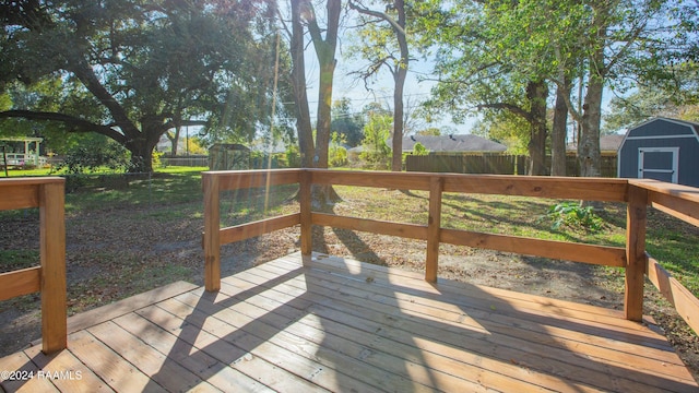 wooden terrace with a storage shed and a yard