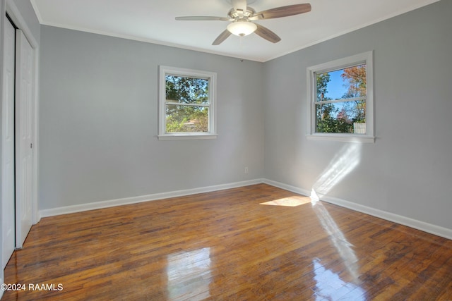 unfurnished bedroom featuring ceiling fan, dark hardwood / wood-style flooring, ornamental molding, and a closet