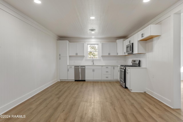 kitchen with sink, white cabinetry, light hardwood / wood-style flooring, stainless steel appliances, and decorative backsplash