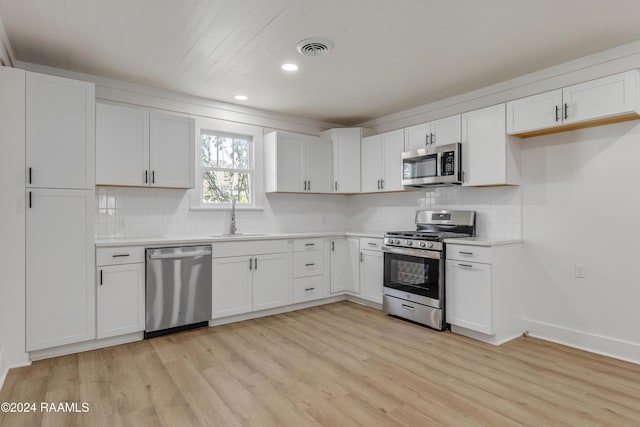 kitchen with sink, stainless steel appliances, light hardwood / wood-style floors, white cabinets, and decorative backsplash