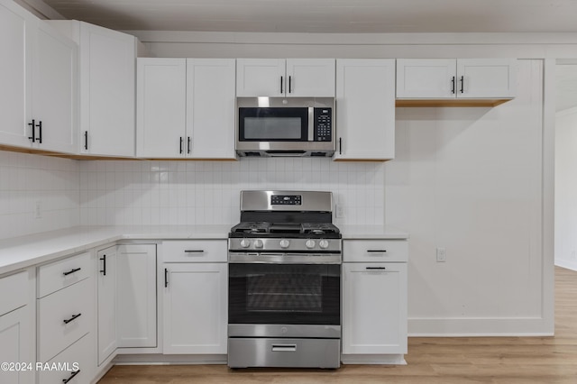 kitchen with stainless steel appliances, white cabinetry, and light hardwood / wood-style flooring