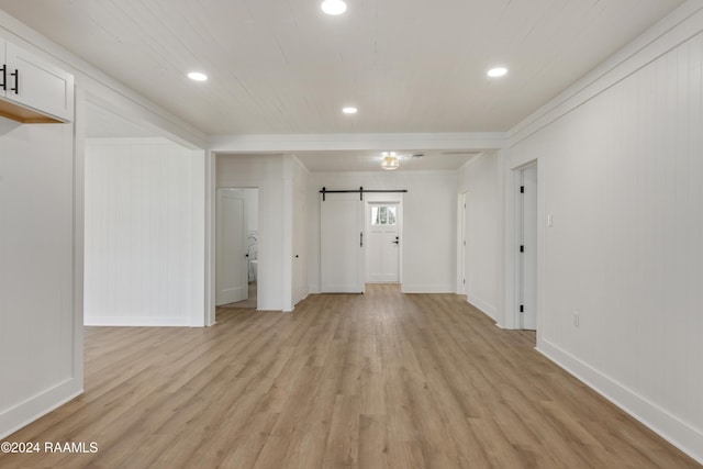 unfurnished living room with light hardwood / wood-style floors and a barn door