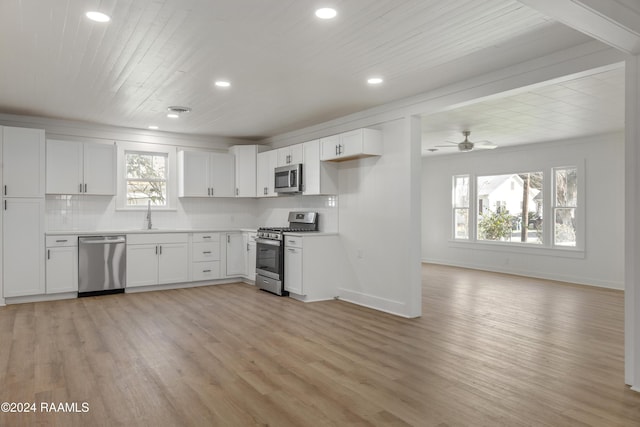 kitchen with appliances with stainless steel finishes, white cabinetry, plenty of natural light, tasteful backsplash, and light wood-type flooring