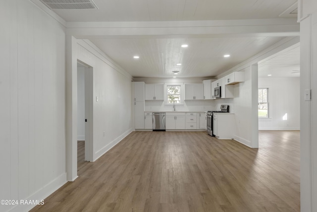 kitchen featuring white cabinetry, appliances with stainless steel finishes, light hardwood / wood-style floors, and decorative backsplash