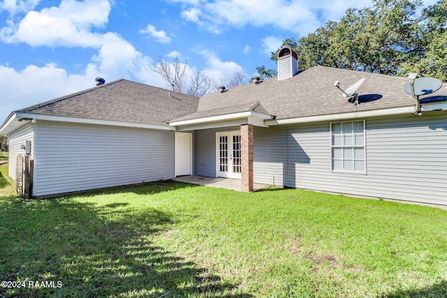 rear view of property featuring french doors, a patio area, and a lawn