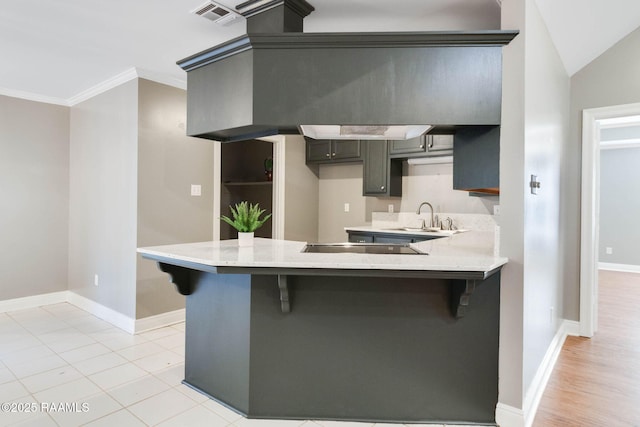 kitchen featuring visible vents, a sink, a breakfast bar area, and a peninsula