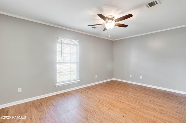 spare room featuring light wood-style flooring, visible vents, baseboards, crown molding, and a ceiling fan