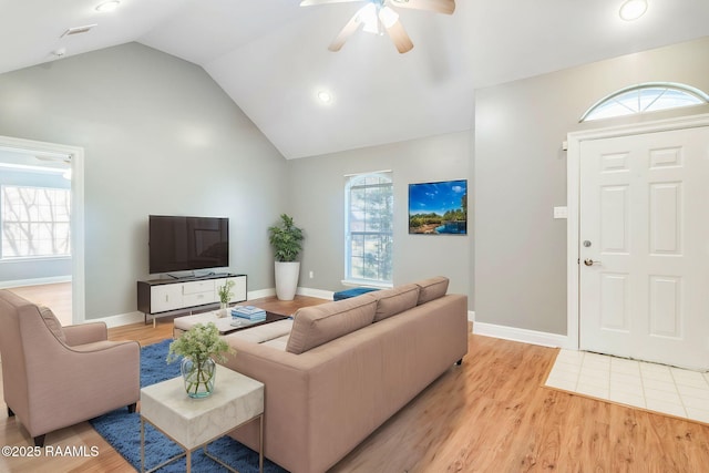 living room featuring vaulted ceiling, ceiling fan, light wood-style floors, and a healthy amount of sunlight