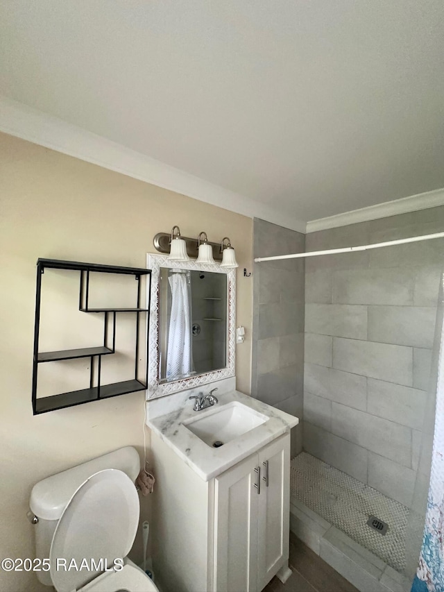 bathroom featuring crown molding, a tile shower, toilet, and vanity