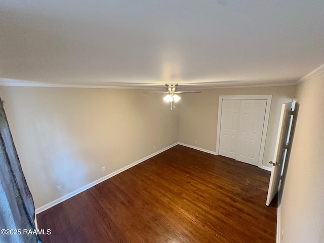 empty room with crown molding, dark wood-style floors, baseboards, and ceiling fan