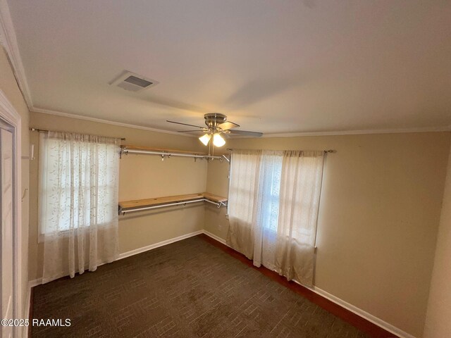 empty room with baseboards, ceiling fan, visible vents, and crown molding