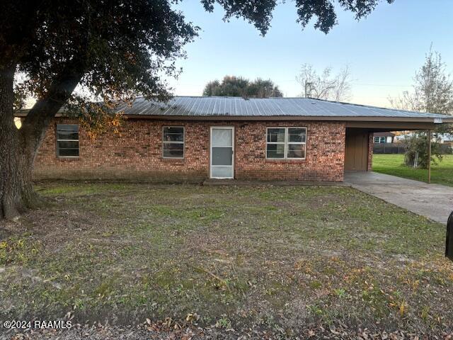 ranch-style home featuring a front lawn and a carport