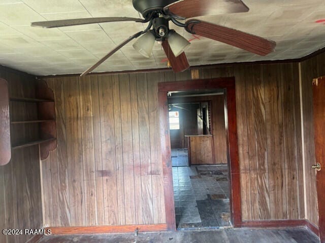 spare room with ceiling fan and wood walls