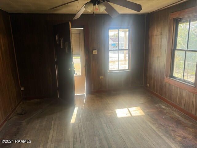 empty room featuring hardwood / wood-style flooring, a healthy amount of sunlight, and wooden walls