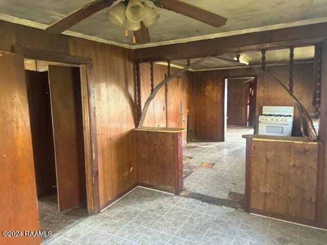 spare room with ceiling fan, crown molding, and wood walls