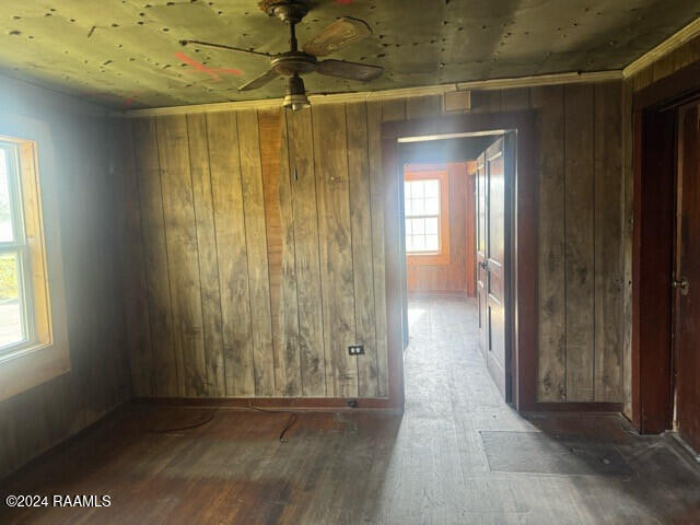 empty room featuring ceiling fan, dark hardwood / wood-style flooring, and wooden walls