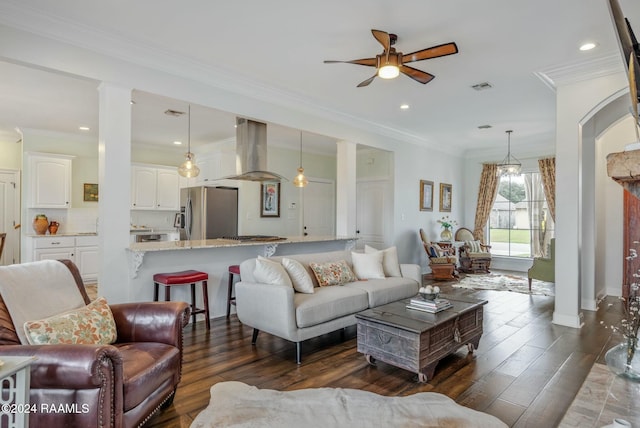 living room with crown molding, dark hardwood / wood-style floors, ceiling fan, and ornate columns