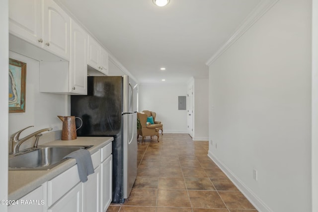 kitchen featuring stainless steel refrigerator, white cabinetry, sink, tile patterned flooring, and ornamental molding