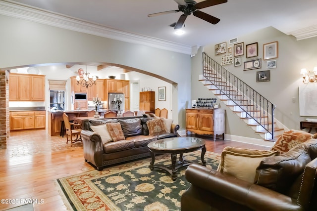 living room featuring ceiling fan with notable chandelier, light hardwood / wood-style floors, and crown molding