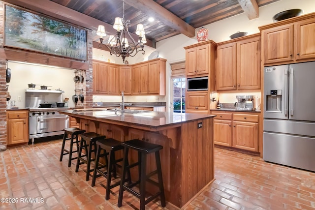 kitchen with beamed ceiling, a notable chandelier, stainless steel appliances, and a kitchen island with sink