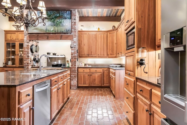 kitchen featuring dark stone counters, an inviting chandelier, sink, built in microwave, and beamed ceiling