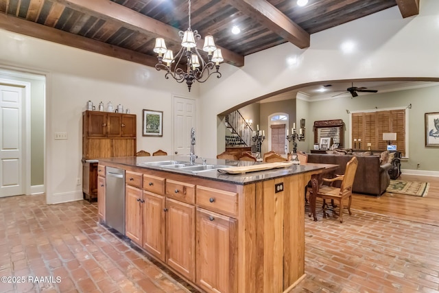 kitchen with ceiling fan with notable chandelier, sink, beam ceiling, hanging light fixtures, and an island with sink