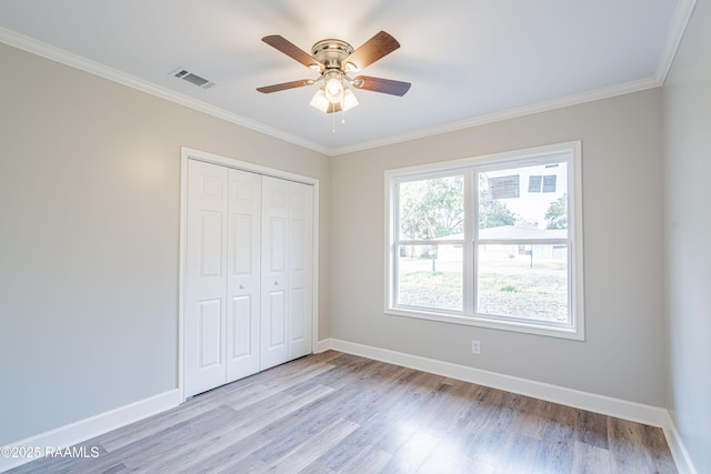 unfurnished bedroom featuring ornamental molding, a closet, ceiling fan, and light wood-type flooring