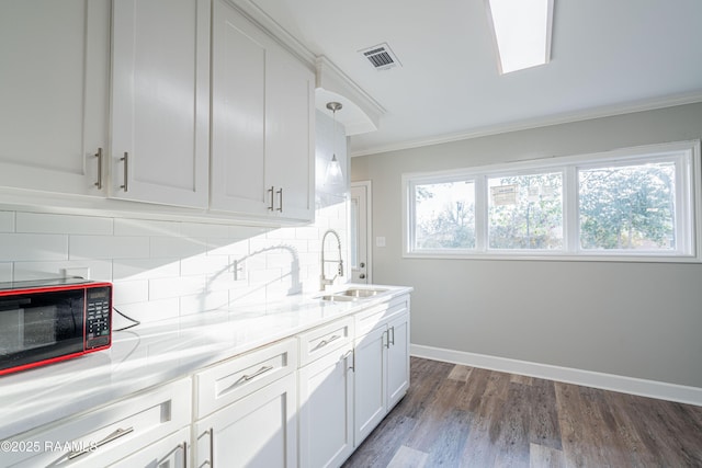 kitchen featuring tasteful backsplash, sink, white cabinets, dark hardwood / wood-style flooring, and ornamental molding