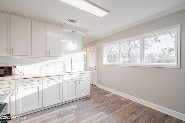 kitchen with sink, crown molding, light wood-type flooring, decorative backsplash, and white cabinets