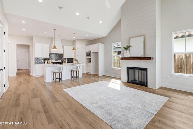 living room with a fireplace, light wood-type flooring, and high vaulted ceiling