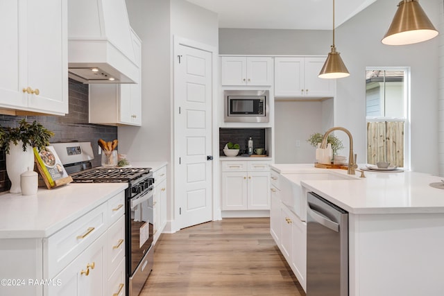 kitchen with sink, decorative light fixtures, decorative backsplash, white cabinets, and appliances with stainless steel finishes