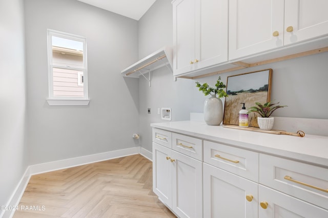 clothes washing area with light parquet floors, cabinets, and hookup for an electric dryer