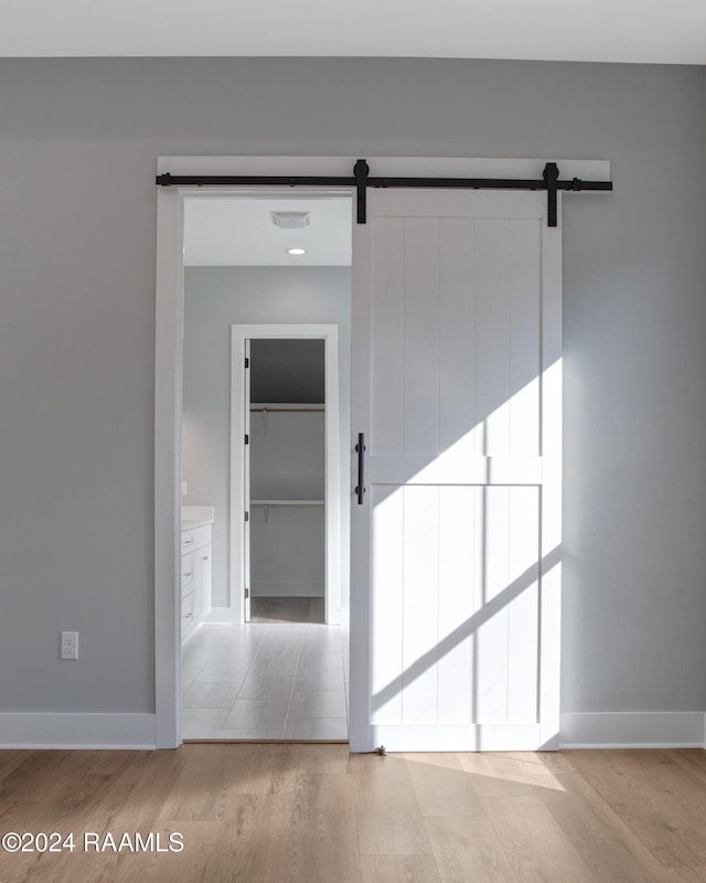 unfurnished room featuring a barn door and light hardwood / wood-style flooring