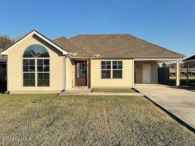 ranch-style home featuring a carport and a front lawn